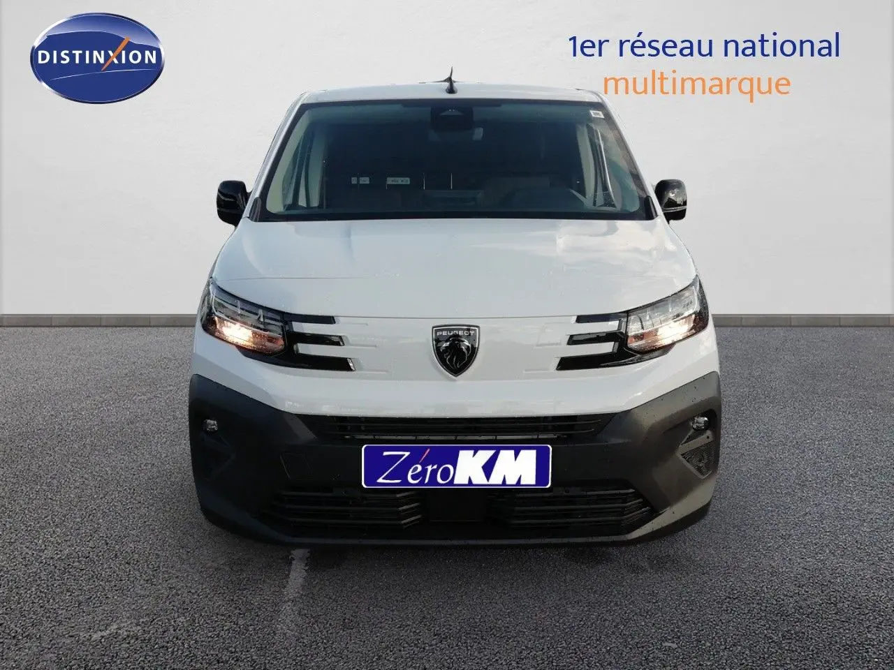 Vue frontale d'un Peugeot Partner blanc Kaolin avec calandre noire et phares allumés sur fond neutre.