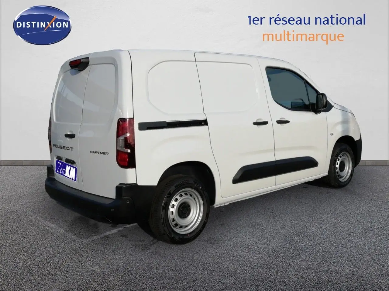 Vue 3/4 arrière droite d’un Peugeot Partner blanc Kaolin, fourgon utilitaire avec protections noires sur les portières.