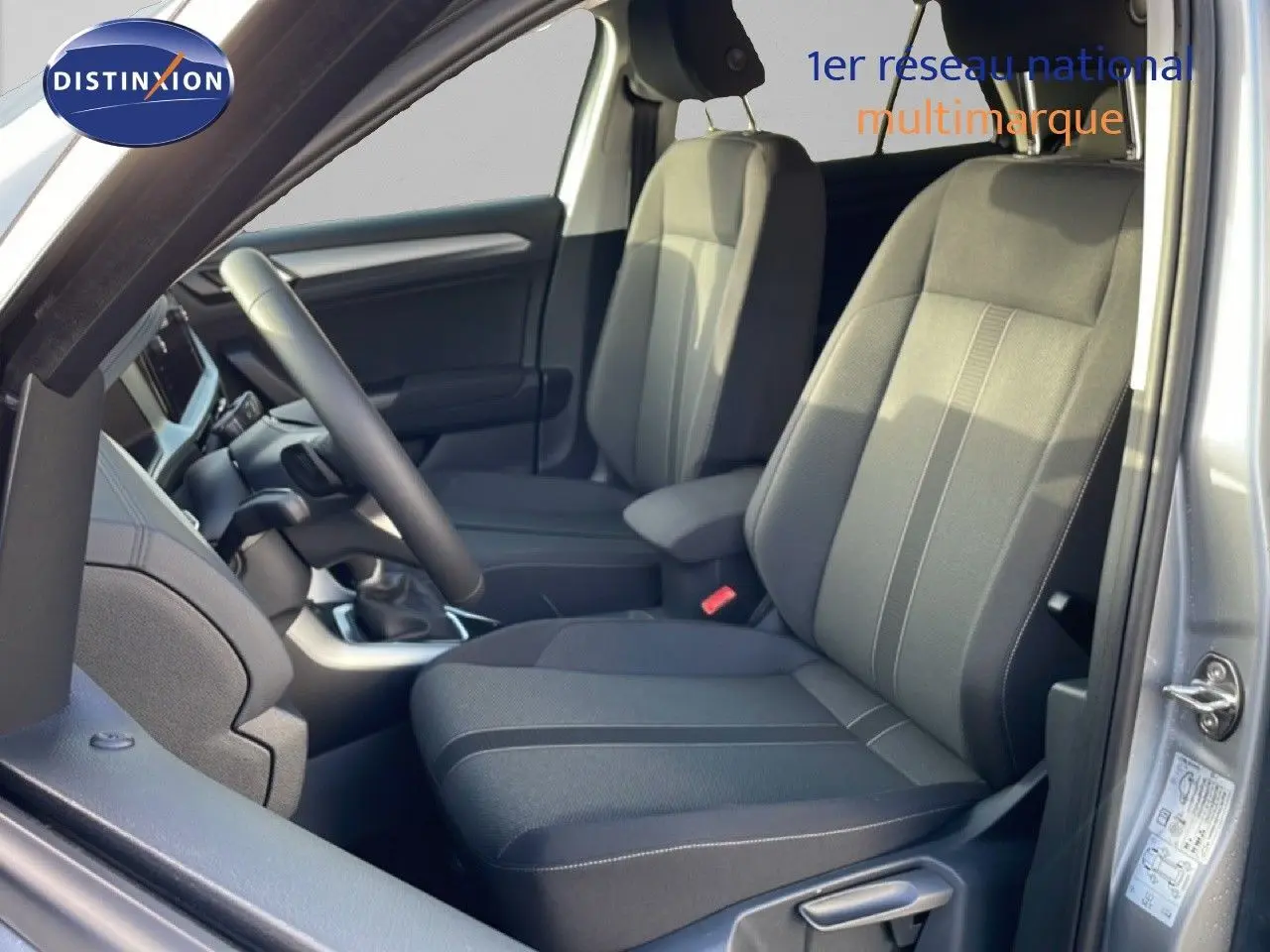 Vue intérieure côté conducteur du Volkswagen T-Roc gris pyrite métal, mettant en valeur les sièges tissu noir et le volant.