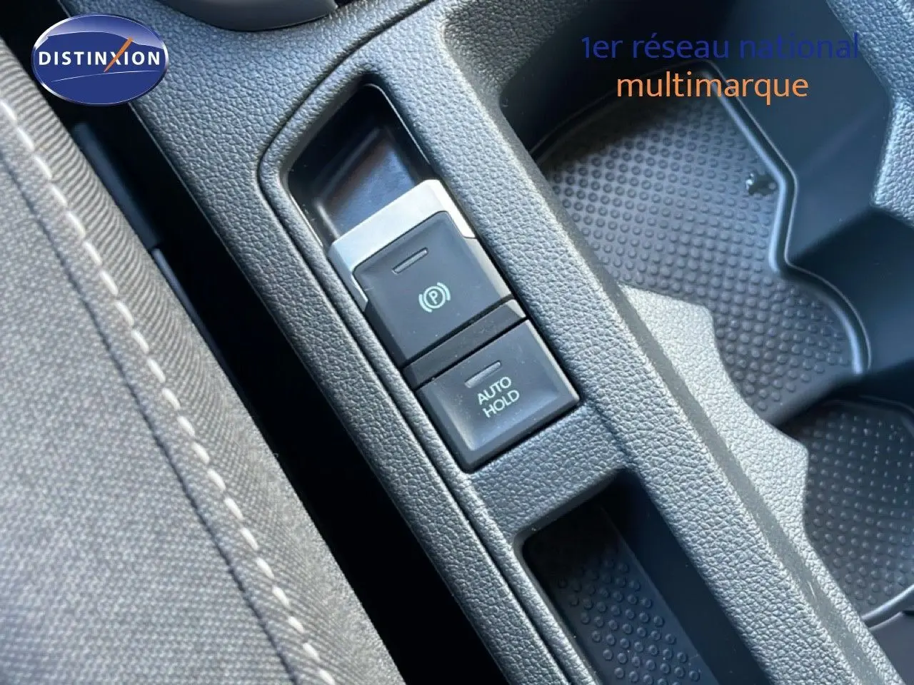 Gros plan sur la console centrale du Volkswagen T-Roc 2025, montrant les boutons de frein à main électrique et auto hold.