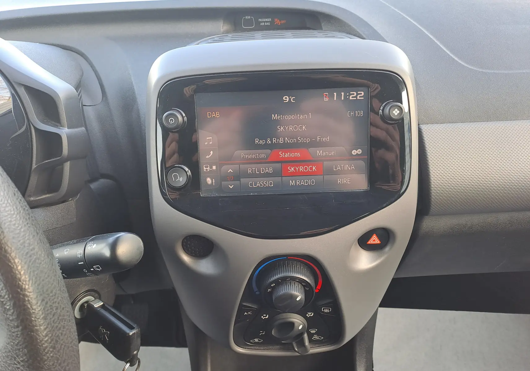 Vue rapprochée du tableau de bord gris et noir de la Peugeot 108 2020 avec écran tactile affichant la radio Skyrock.