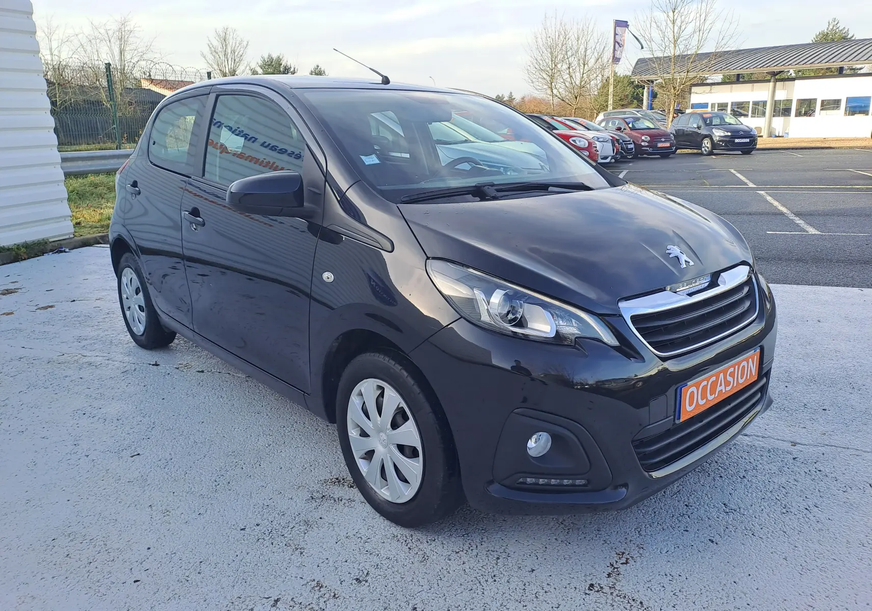Peugeot 108 noire vue en 3/4 avant droit, compacte 5 portes avec phares LED et plaque "OCCASION" visible.