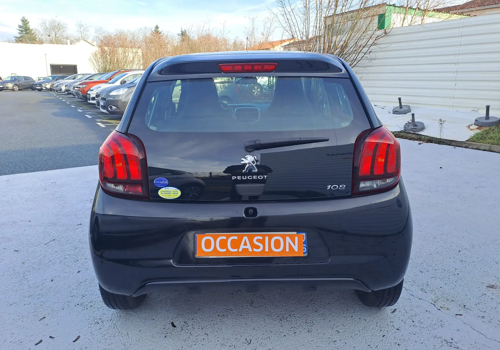 Vue arrière d'une Peugeot 108 noire de 2020 avec plaque "OCCASION" et feux arrière rouges bien visibles.