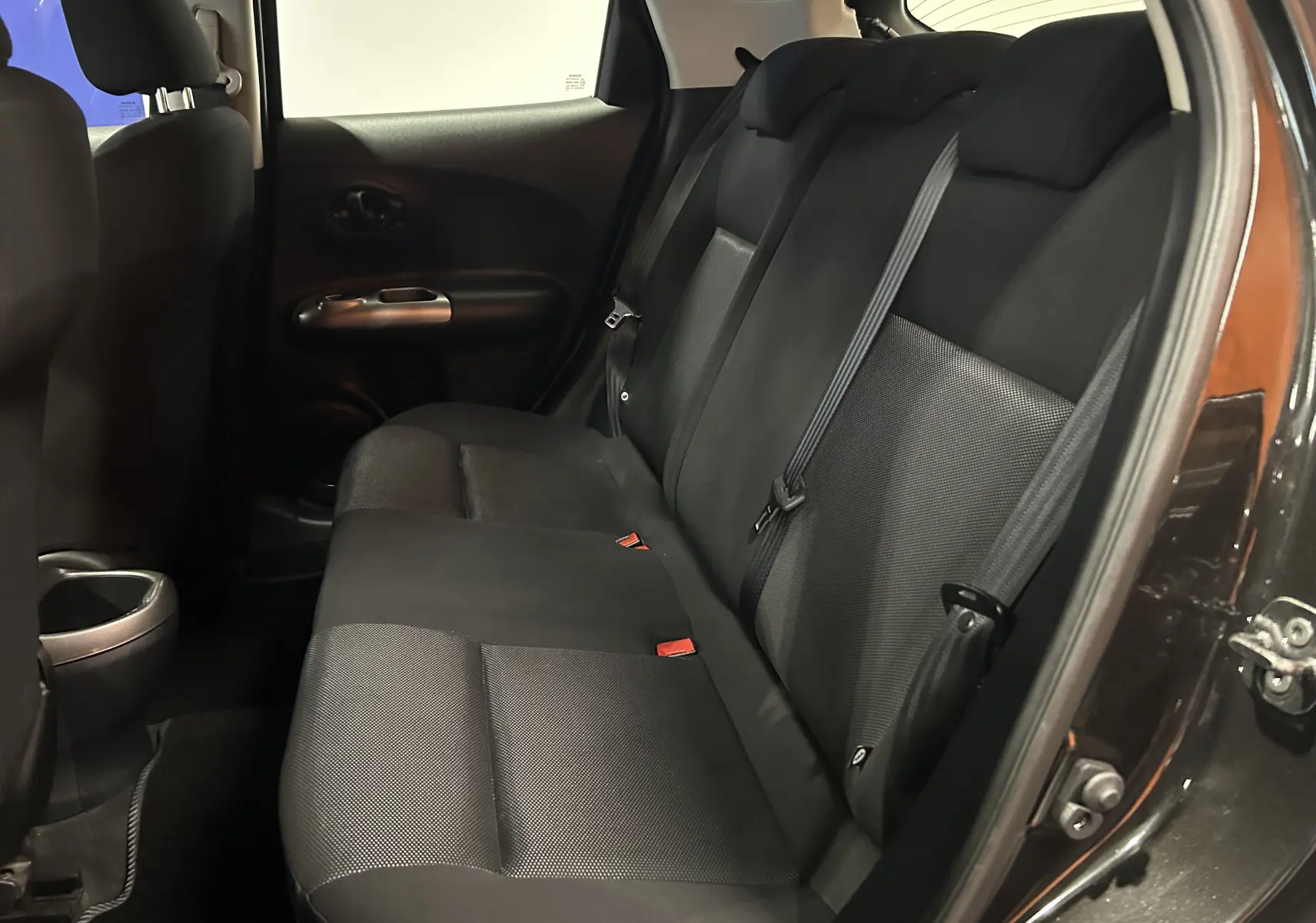 Vue intérieure côté droit des sièges arrière noirs en tissu du Nissan Juke dci 110 Acenta avec portières ouvertes.