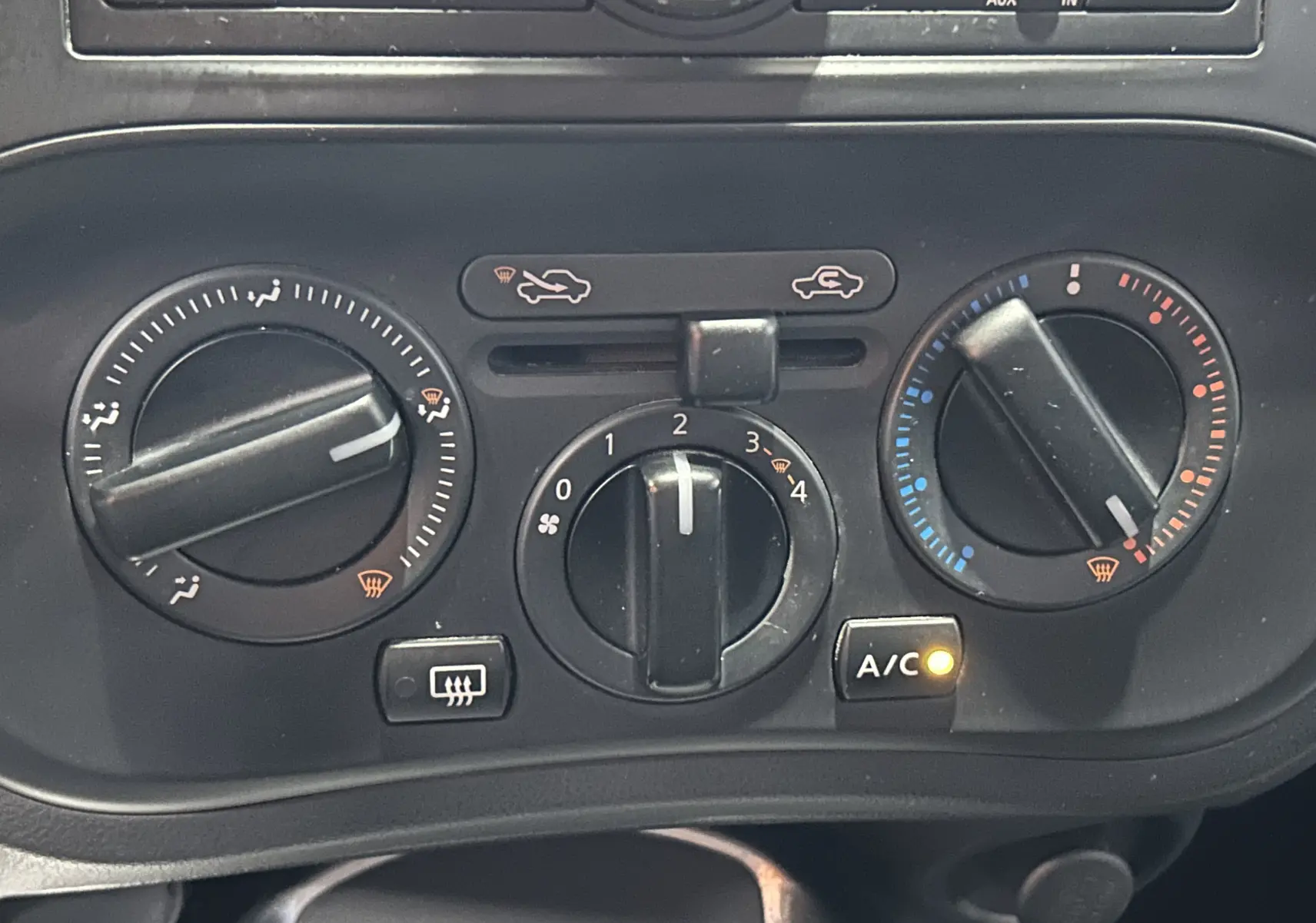 Vue rapprochée des commandes de climatisation du Nissan Juke noir métal, avec bouton A/C allumé et réglages manuels visibles.