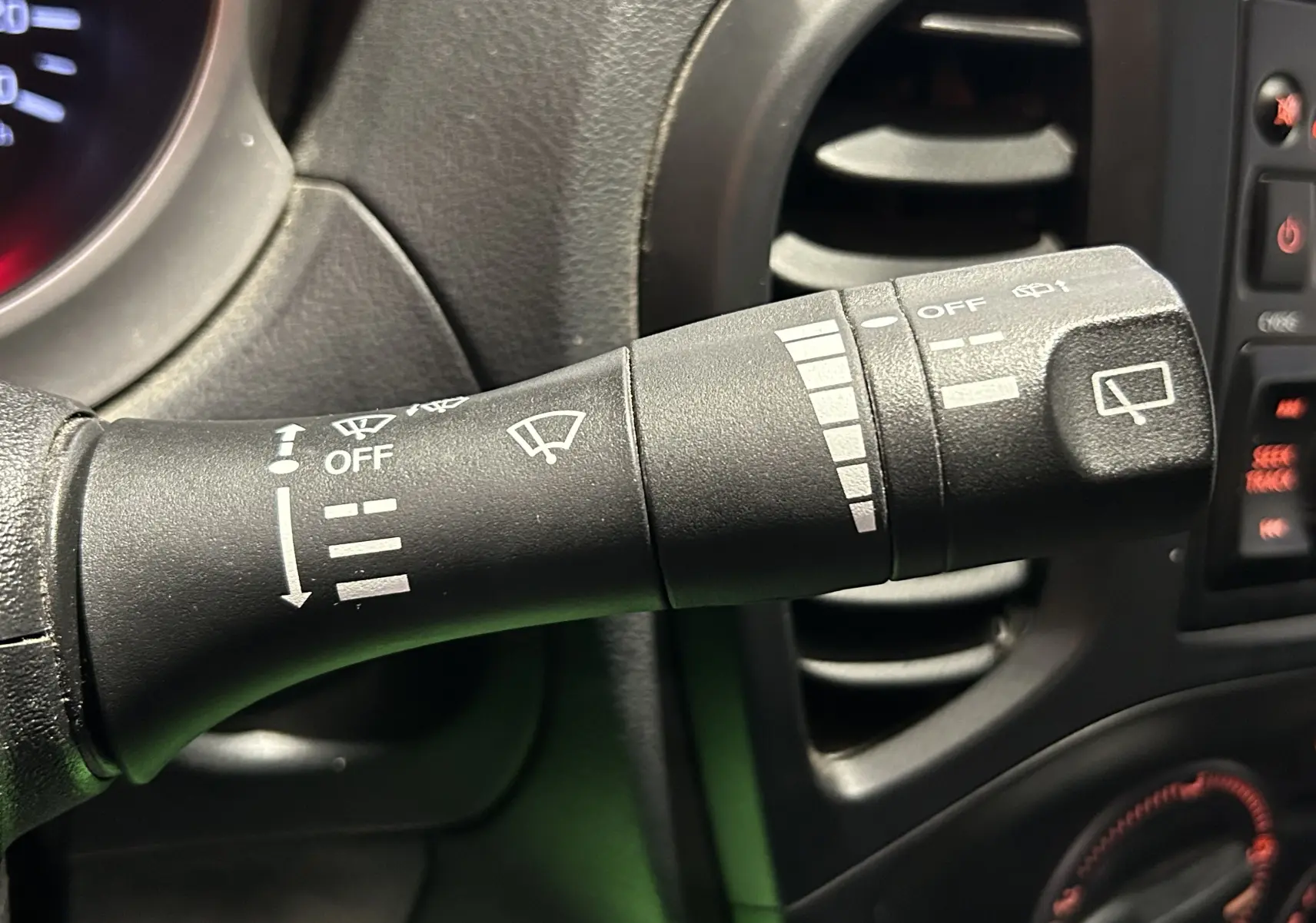 Gros plan sur la manette d’essuie-glace noire à gauche du volant du Nissan Juke dci 110 Acenta 2012.