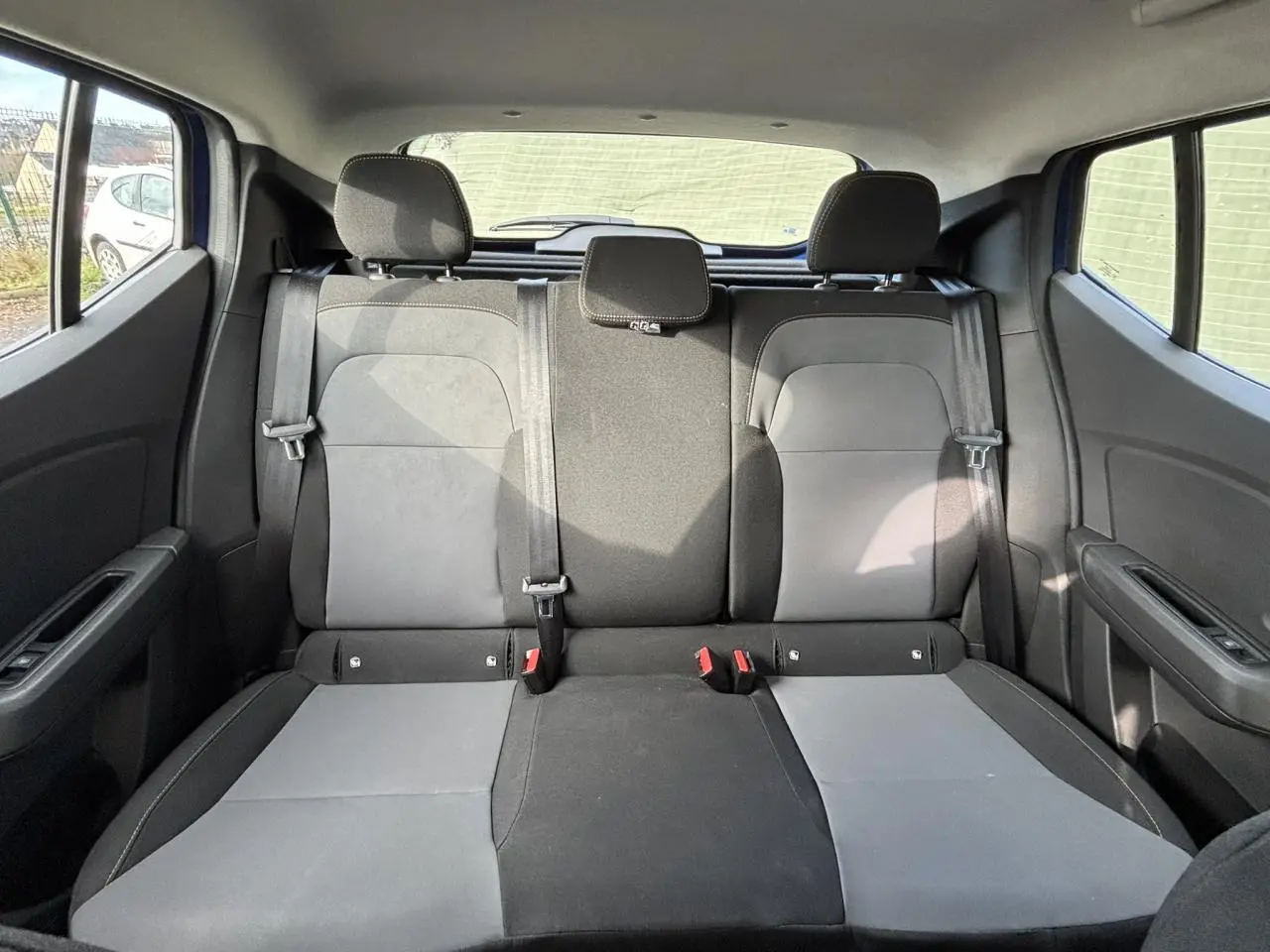 Vue arrière intérieure montrant la banquette arrière bicolore grise et noire du Dacia Sandero Stepway 2025.