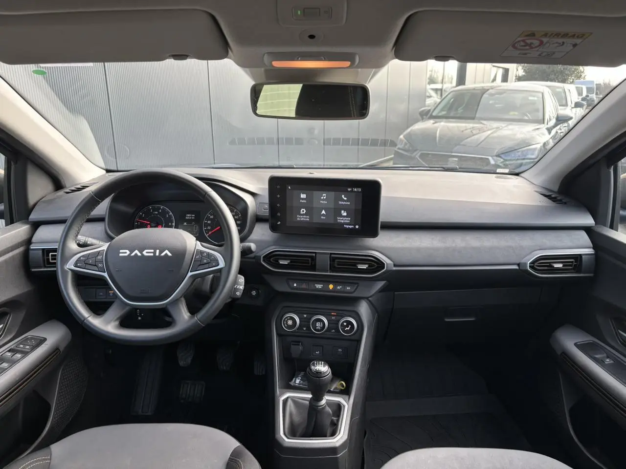 Vue intérieure avant du tableau de bord et volant Dacia d'une Sandero Stepway Bleu Iron avec écran tactile et boîte manuelle.