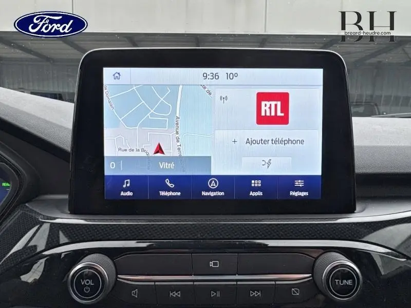 Écran tactile central du Ford Kuga 2022 affichant la navigation et la radio RTL, tableau de bord noir brillant.