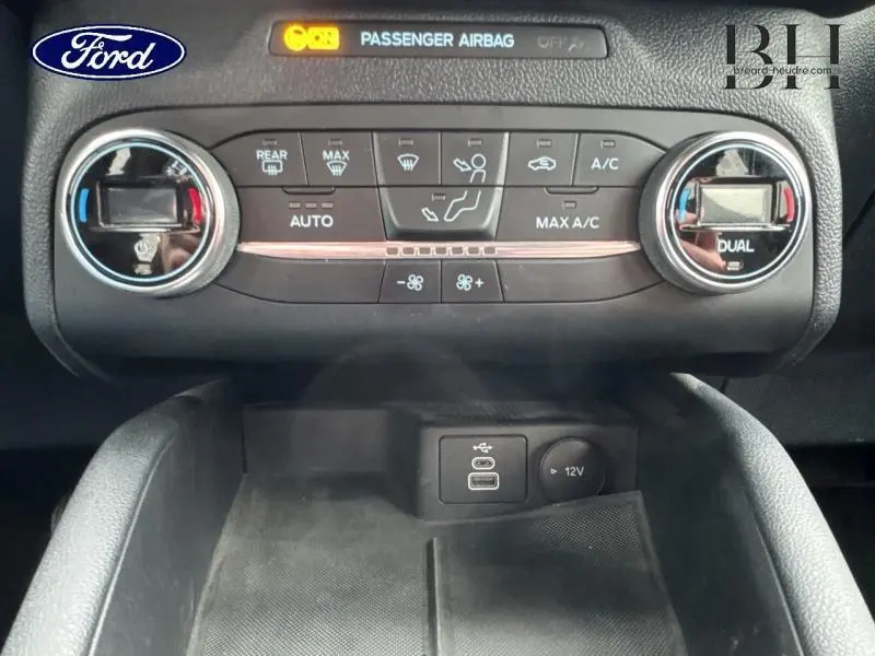 Vue rapprochée de la console centrale du Ford Kuga 2022, montrant les commandes de climatisation bi-zone et prises USB et 12V.