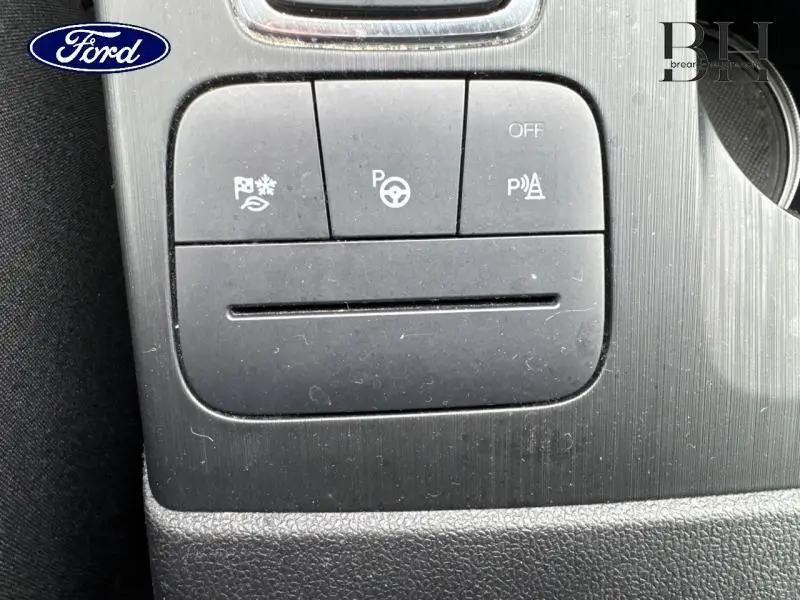 Gros plan sur les boutons de commande noirs du tableau de bord du Ford Kuga gris Solar Métallisé.