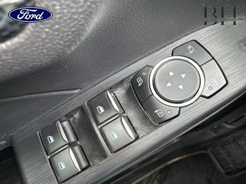 Gros plan sur les commandes de lève-vitres et rétroviseurs côté conducteur du Ford Kuga gris Solar Métallisée 2022.