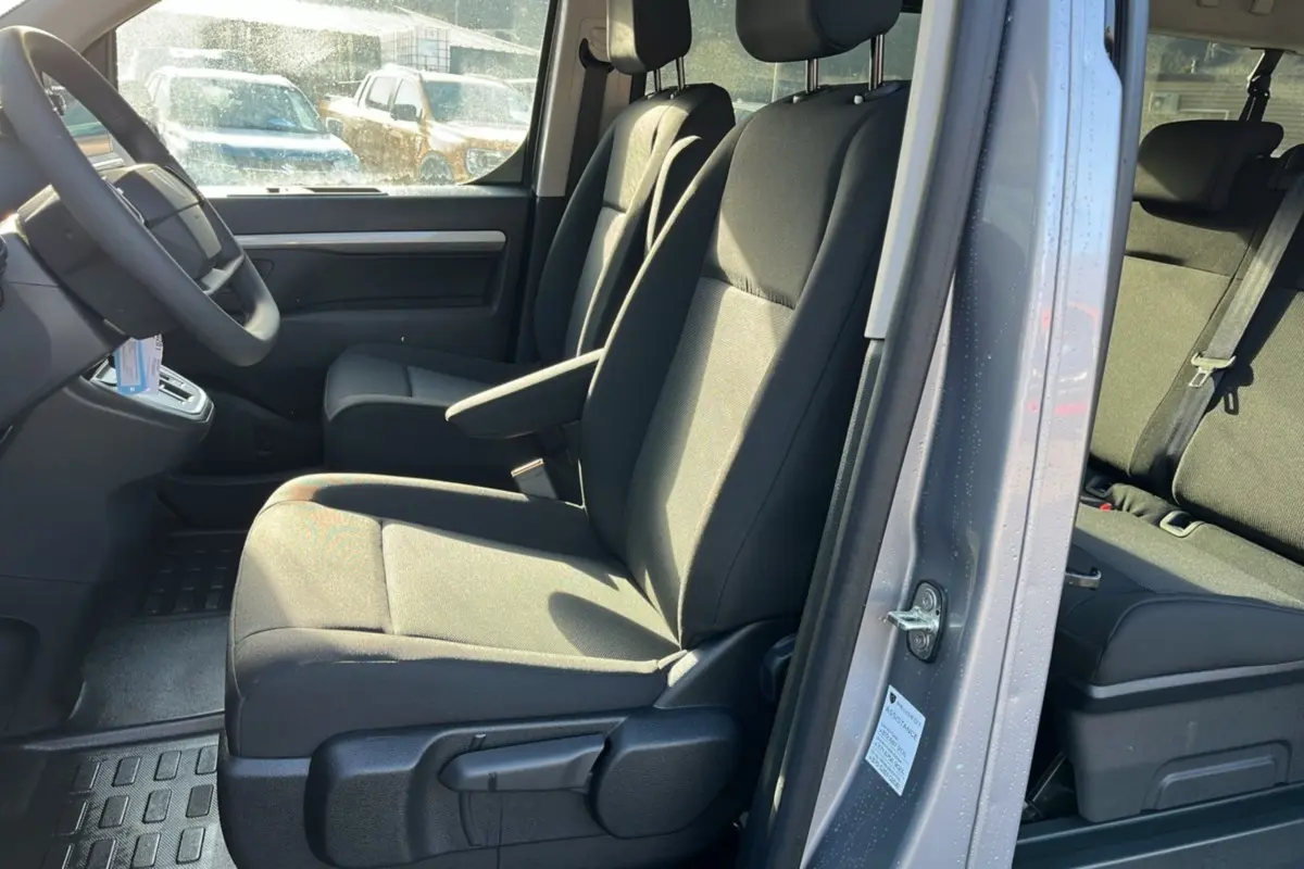 Intérieur du Peugeot Traveller gris acier vu côté gauche, montrant les sièges avant avec accoudoir central.