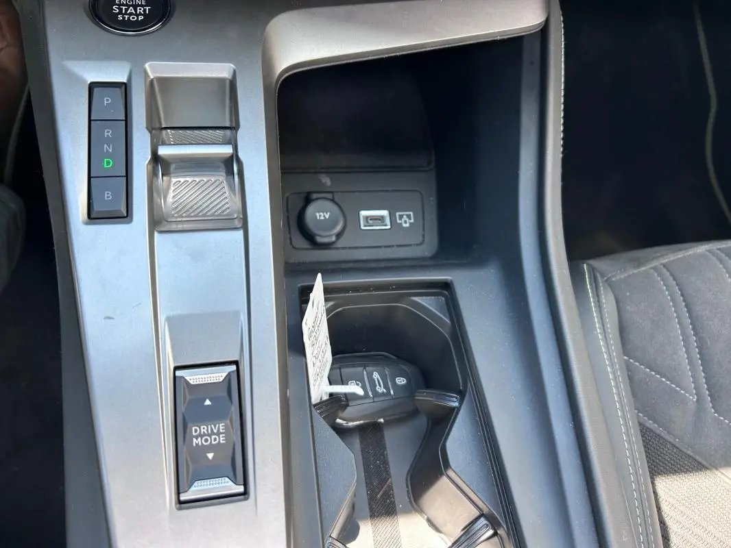 Vue rapprochée de la console centrale de la Peugeot 308 SW PHEV 225 GT 2023, avec clé, levier de vitesses et ports USB visibles.