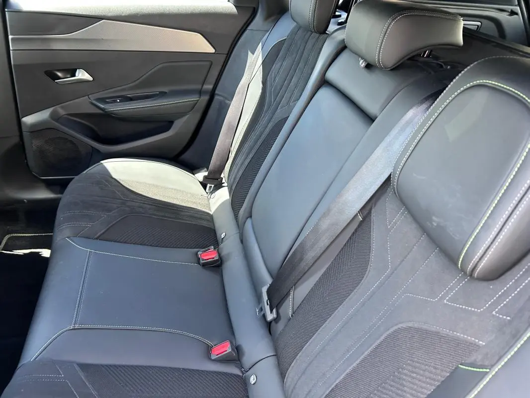 Vue intérieure des sièges arrière en cuir noir avec surpiqûres vertes d'une Peugeot 308 SW PHEV 225 GT 2023.