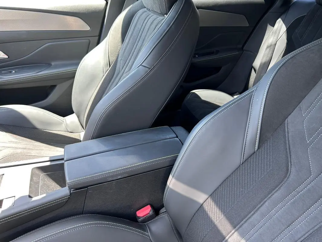 Vue intérieure rapprochée des sièges avant noirs et de l'accoudoir central du Peugeot 308 SW PHEV 225 GT 2023.