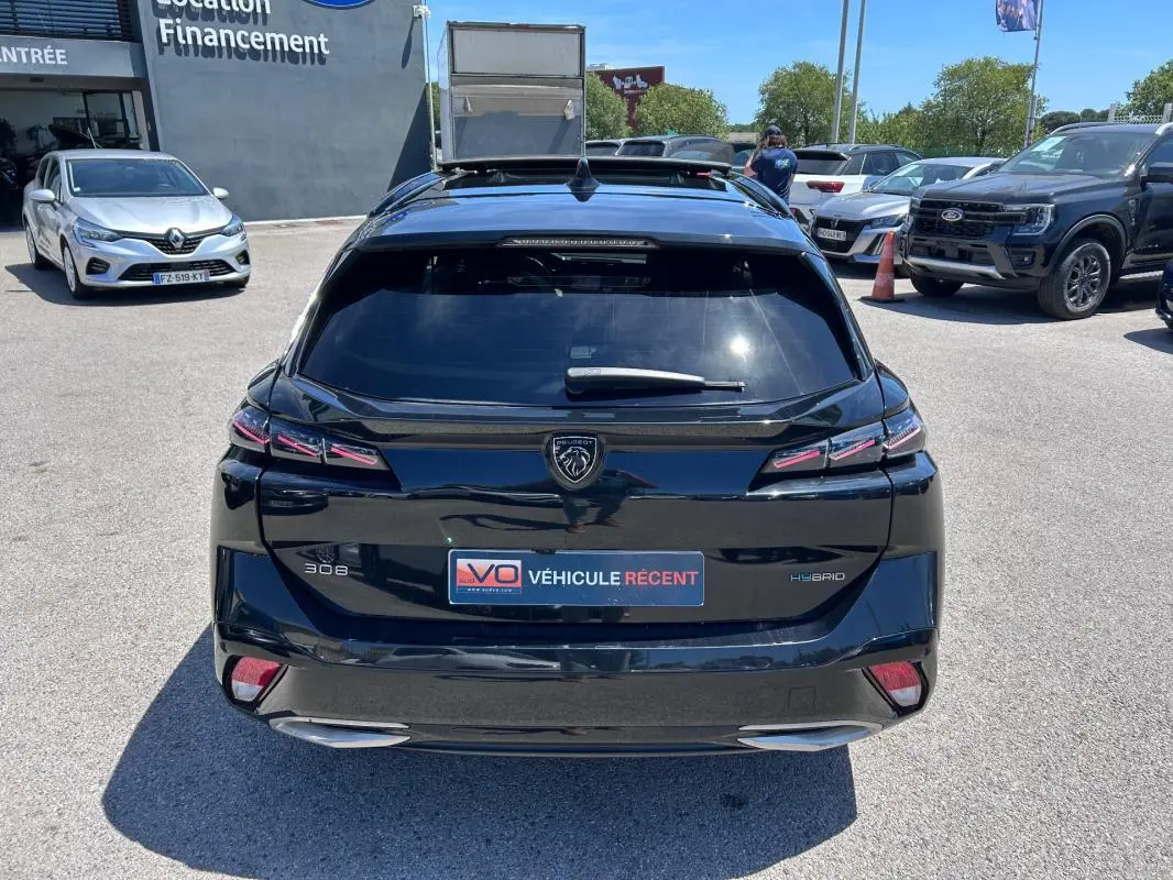 Vue arrière d'une Peugeot 308 SW PHEV 225 e-EAT8 GT noire avec feux LED et double sortie d'échappement visible.