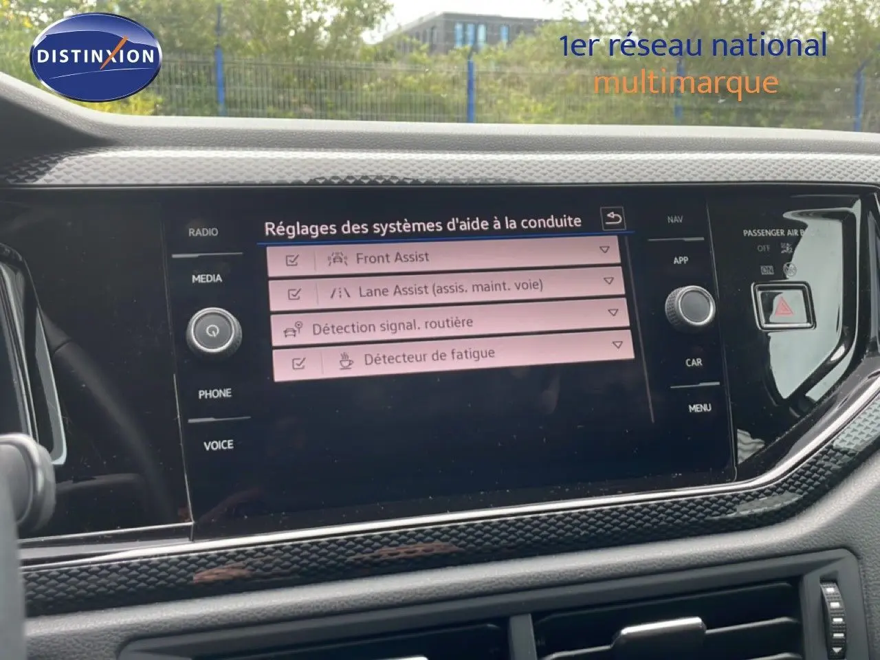 Vue rapprochée de l’écran tactile central du Volkswagen Polo blanc, affichant les réglages des aides à la conduite.