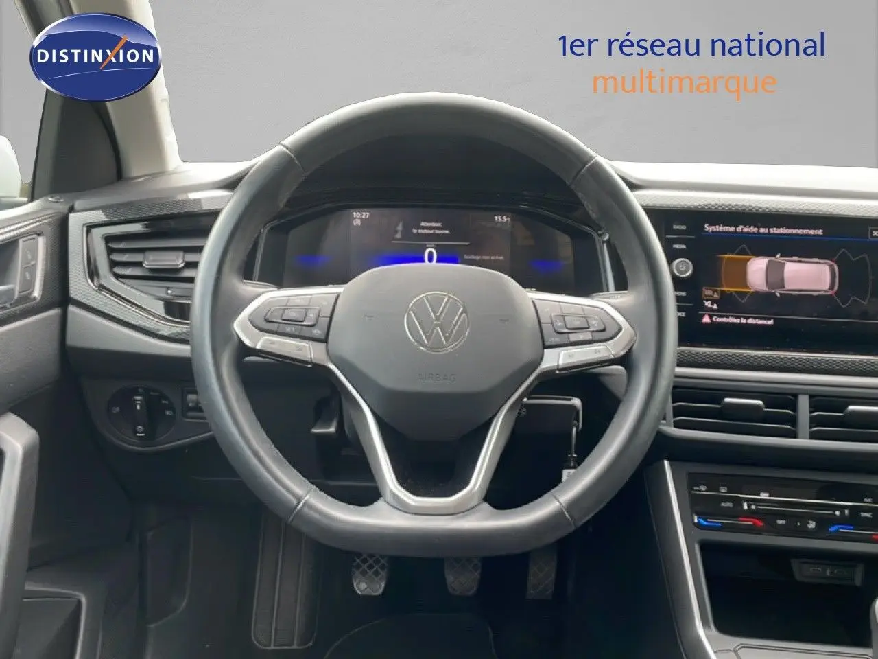 Vue intérieure centrée sur le volant cuir noir d'une Volkswagen Polo blanche de 2022 avec tableau de bord digital et écran tactile.