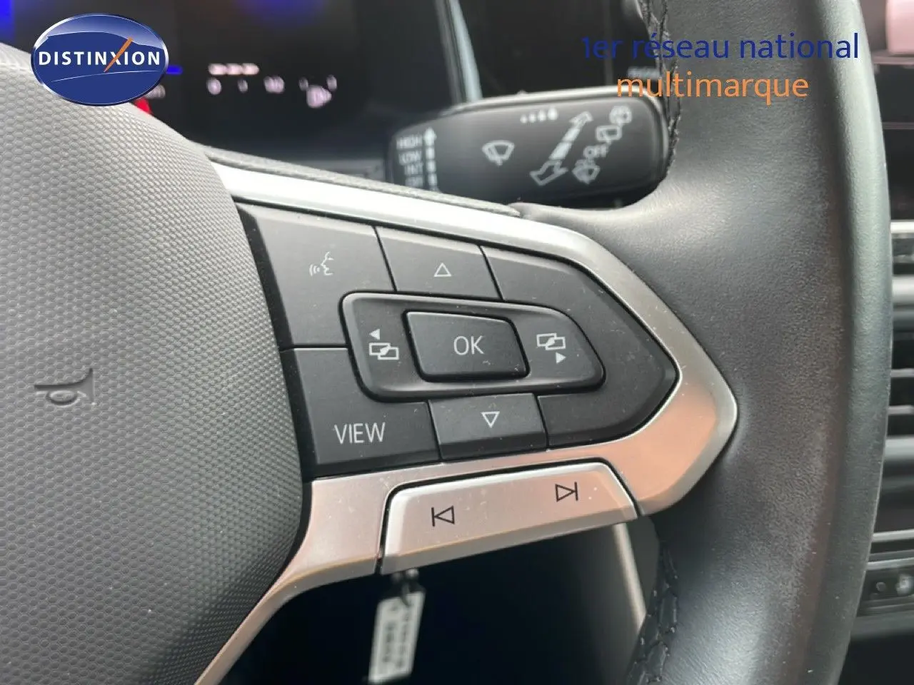Gros plan sur les commandes au volant cuir noir d'une Volkswagen Polo blanche, mettant en valeur les boutons multifonctions.