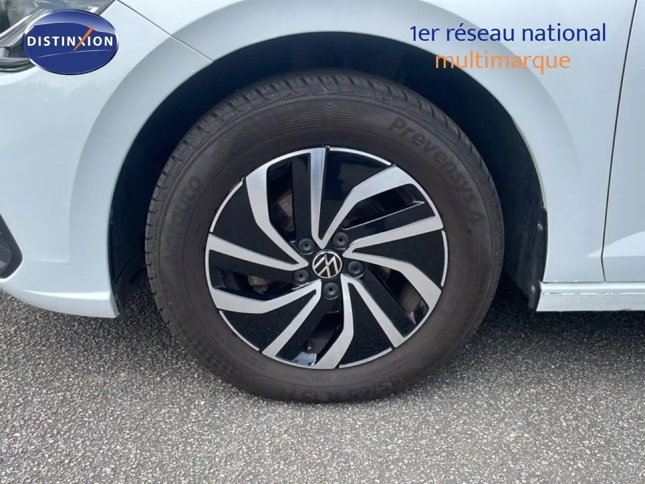 Gros plan sur la roue avant gauche d'une Volkswagen Polo blanc pur, avec jante alliage bicolore au design moderne.