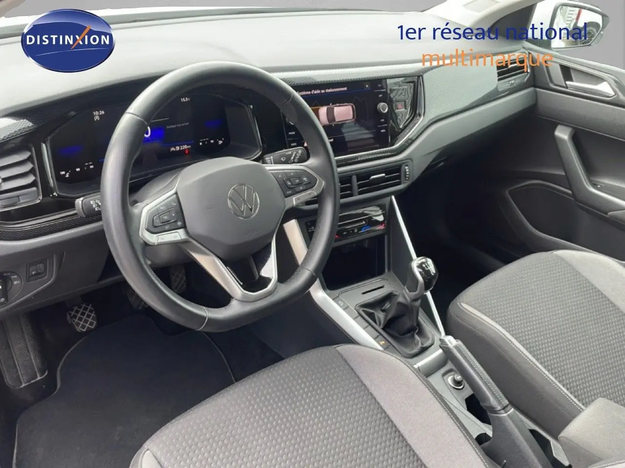 Vue intérieure de la Volkswagen Polo 2022, tableau de bord et volant multifonction en cuir, sièges tissu gris.