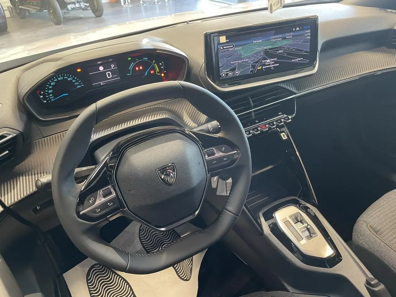 Vue intérieure du poste de conduite du Peugeot 2008 blanc, avec volant compact, tableau de bord numérique et écran tactile 10 pouces.