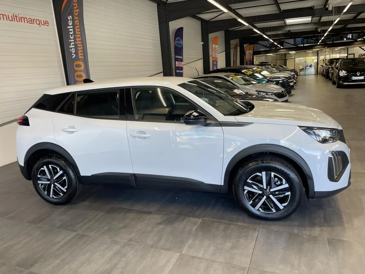 Peugeot 2008 blanc vue de profil côté gauche en intérieur, avec jantes alliage bicolores et rétroviseurs noirs.