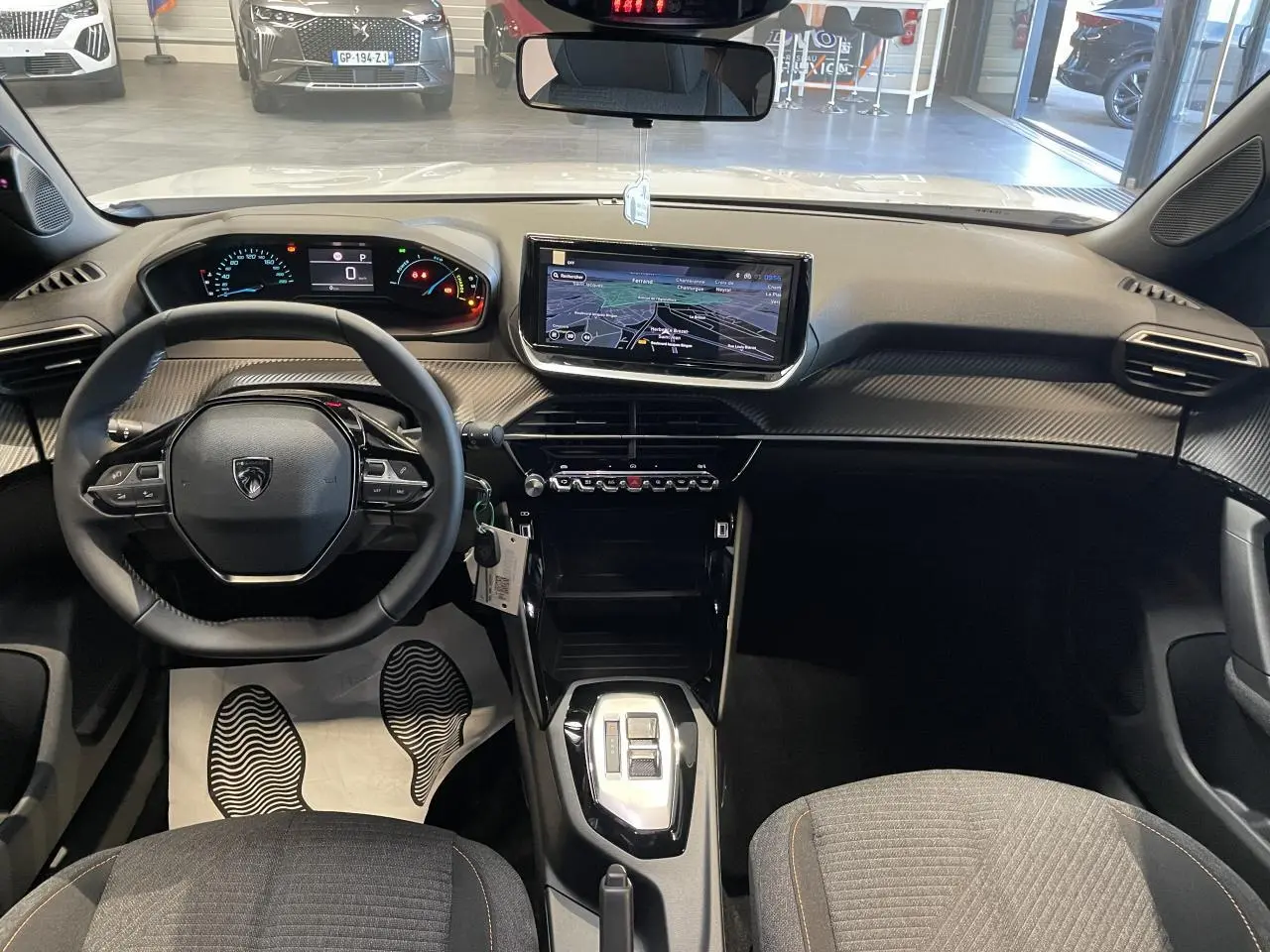 Vue intérieure avant du Peugeot 2008 blanc 2026, tableau de bord avec écran tactile 10'' et volant compact cuir noir.