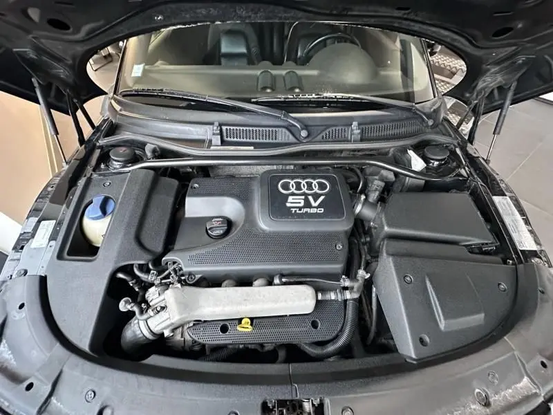 Vue plongeante sur le moteur turbo 5V d'une Audi TT Coupé noire de 2002 avec capot ouvert.