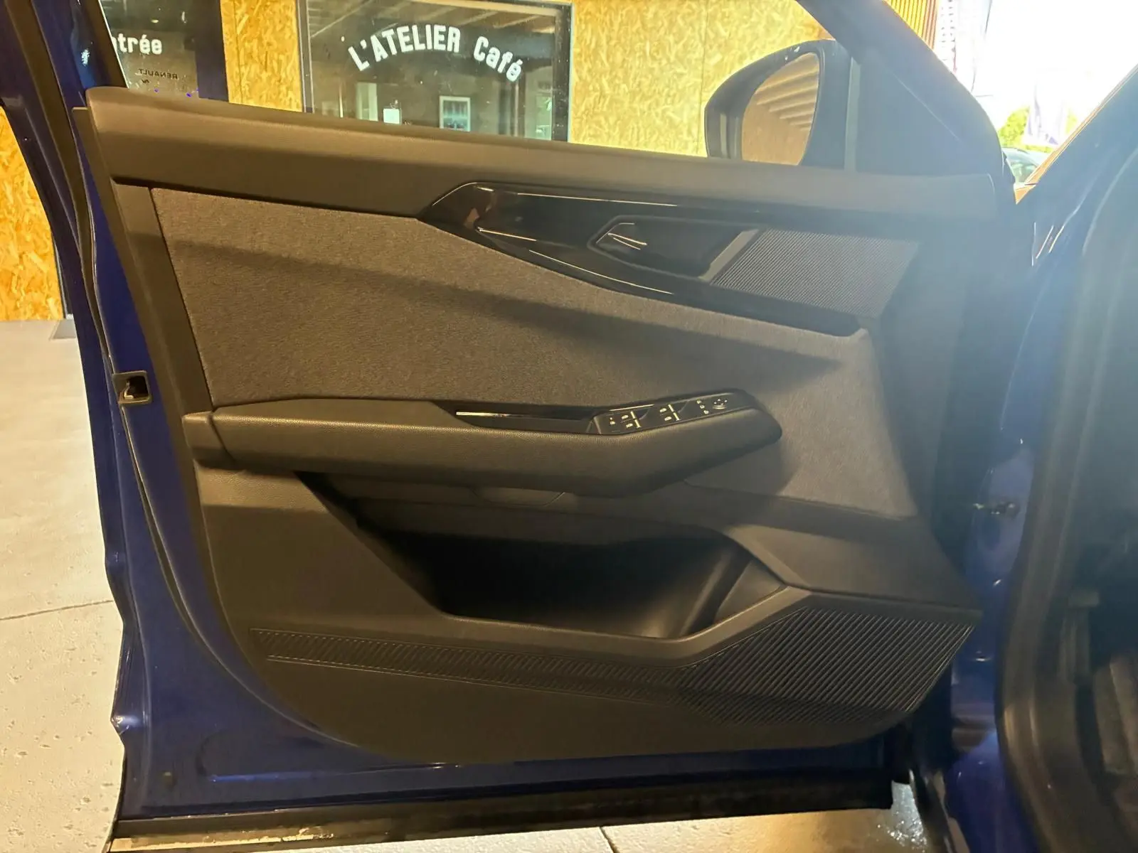 Vue de profil intérieur sur la porte avant gauche bleu du Renault Austral 2024 avec commandes de vitres et haut-parleur intégré.