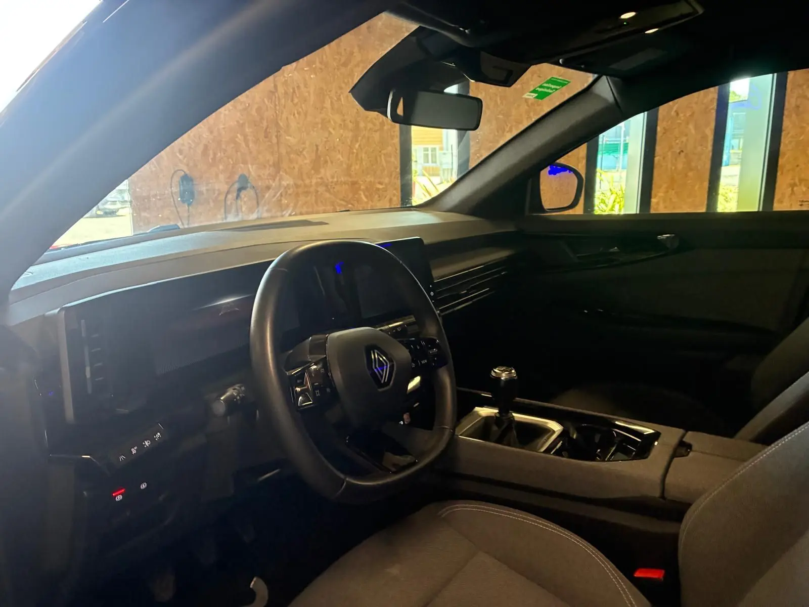 Intérieur du Renault Austral 2024 vu côté conducteur, avec volant multifonction, tableau de bord noir et levier de vitesse manuel.