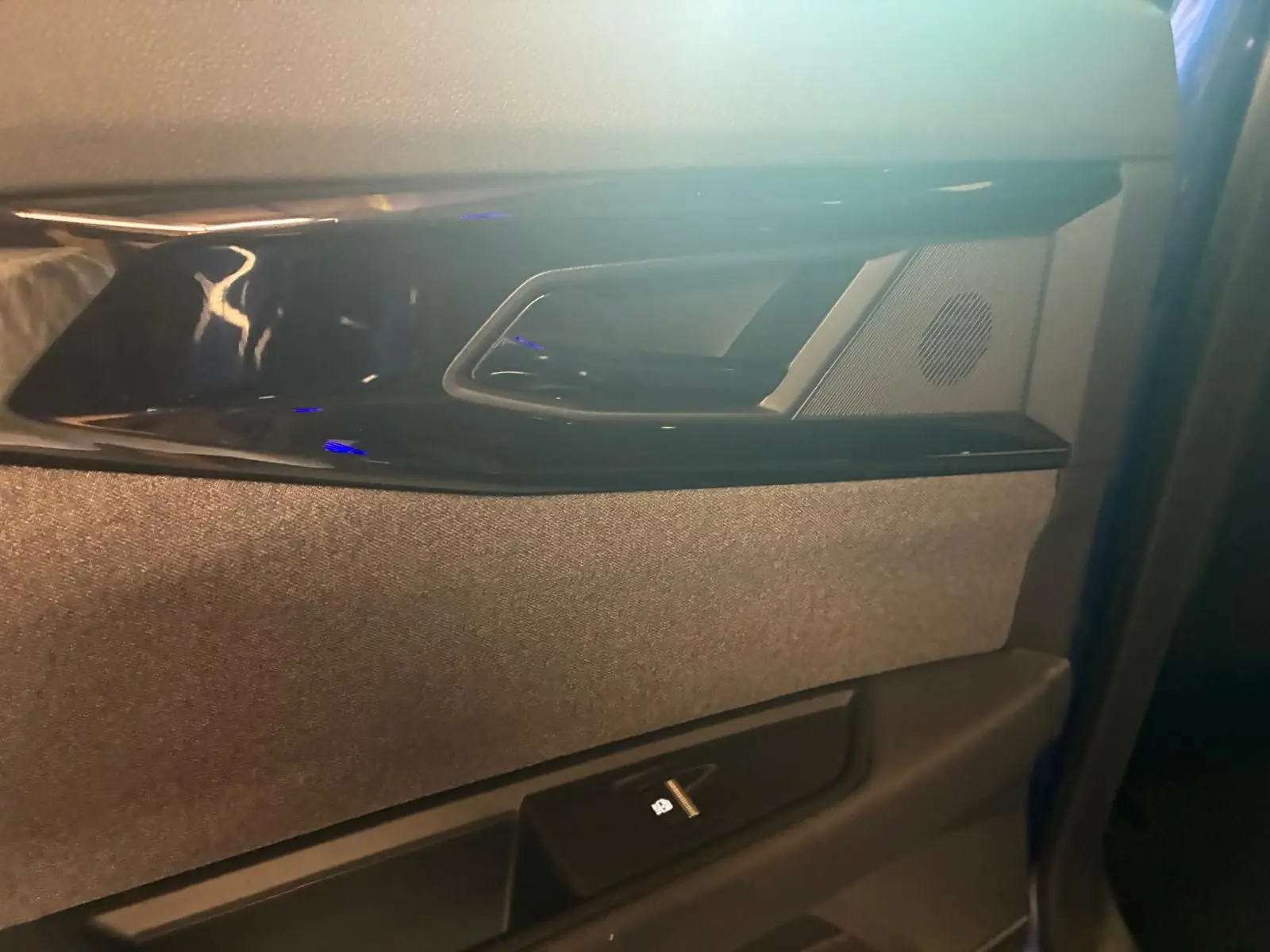 Gros plan sur la poignée intérieure et la commande de vitre côté gauche d’une Renault Austral bleu, finition tissu gris-noir.