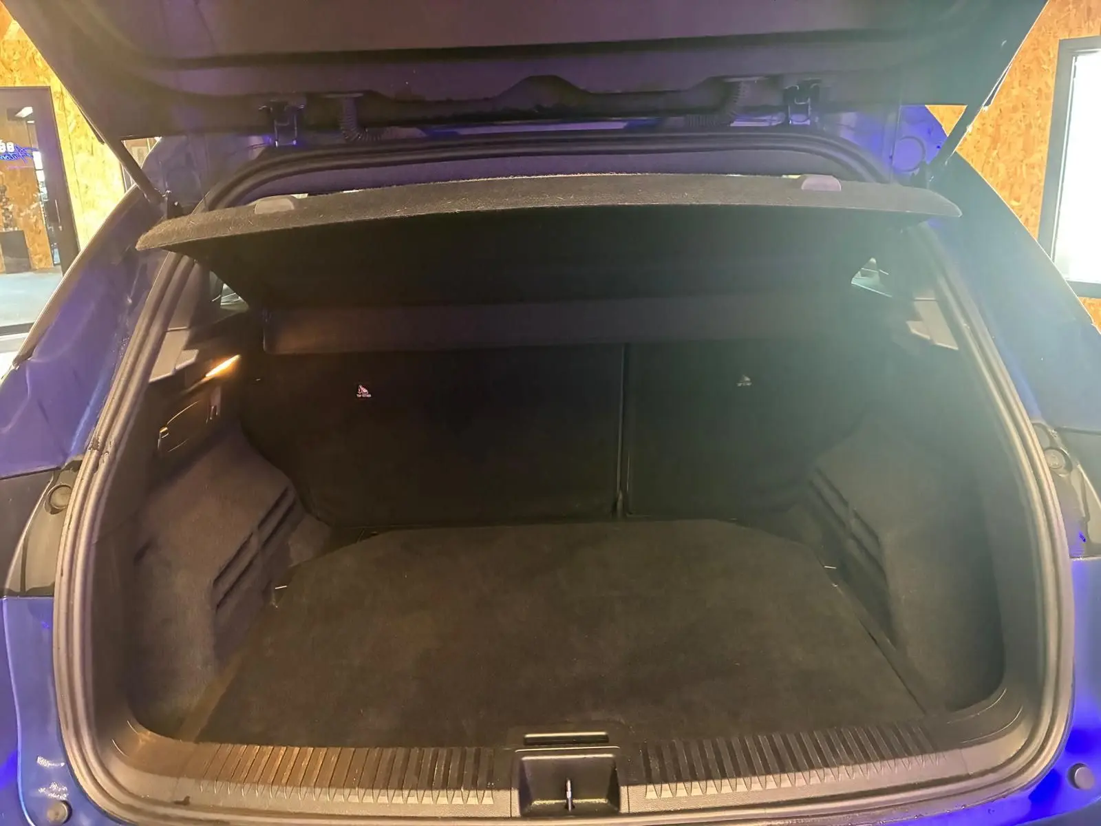 Coffre ouvert vu de l'arrière d'un Renault Austral bleu, montrant un espace de chargement vide et propre.