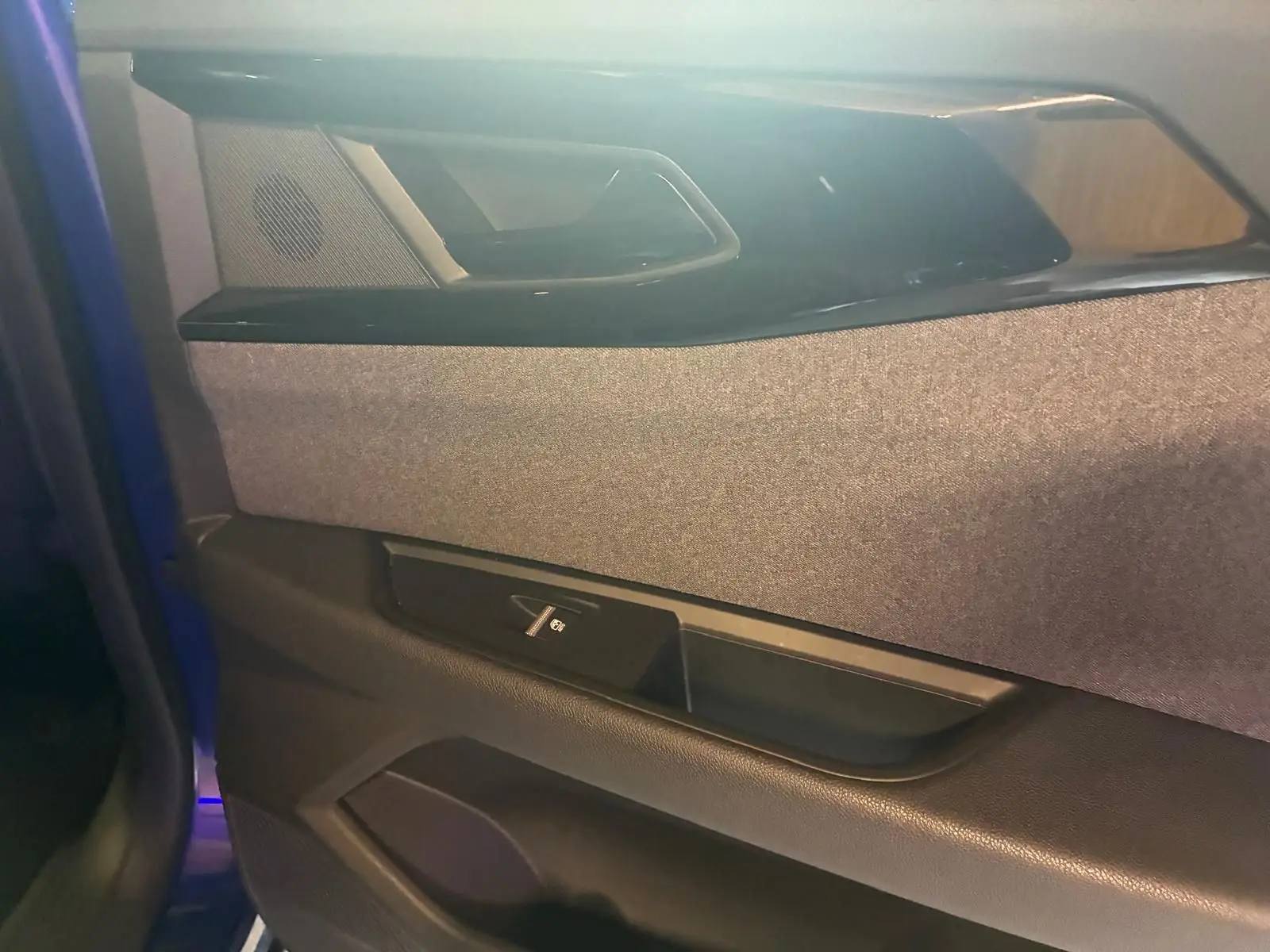 Détail de la porte avant gauche du Renault Austral bleu 2024, montrant le revêtement tissu gris et la commande de vitre électrique.