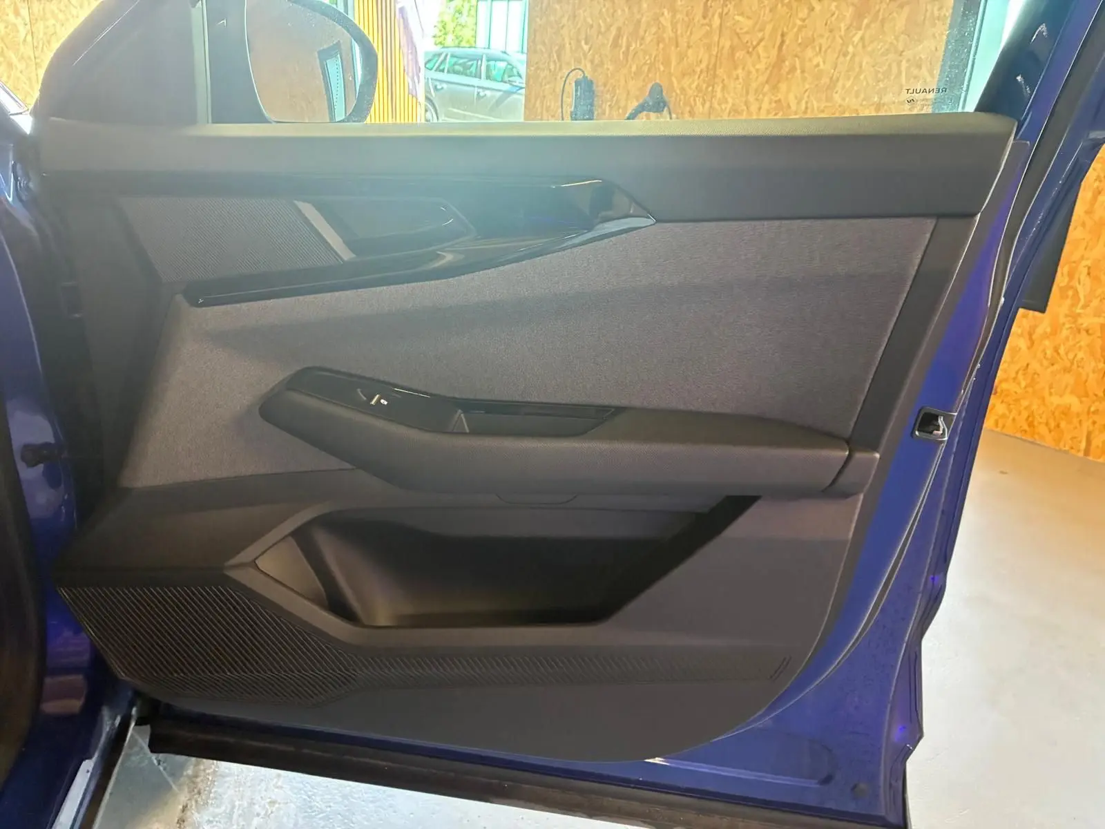 Vue intérieure de la porte avant gauche du Renault Austral bleu 2024, avec habillage tissu gris et garnitures noires.