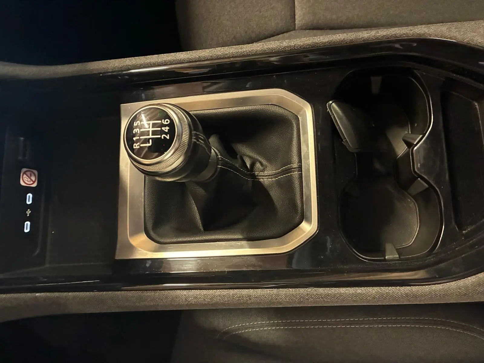 Gros plan sur le levier de vitesse manuel entouré de cuir noir et console centrale brillante dans un Renault Austral bleu 2024.