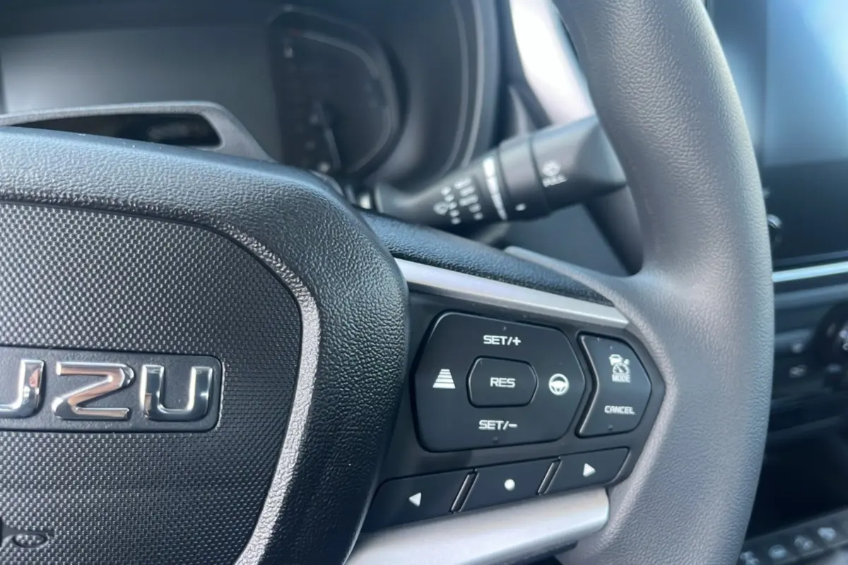 Gros plan sur le volant multifonctions noir de l'Isuzu D-MAX 2026 avec commandes de régulateur de vitesse.