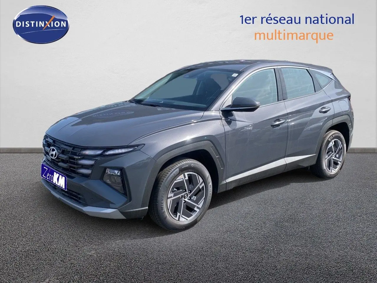 Hyundai Tucson 2026 gris Ecotronic Metal en 3/4 avant droit avec jantes bi-ton et calandre noire distinctive.