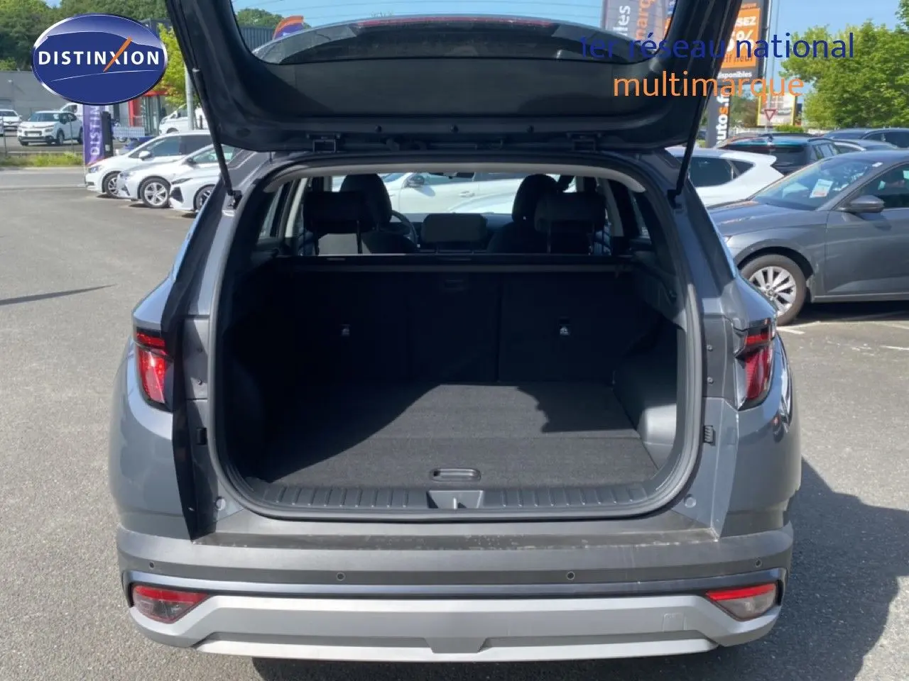 Vue arrière d’un Hyundai Tucson gris Ecotronic Metal 2026 avec coffre ouvert et intérieur spacieux visible.