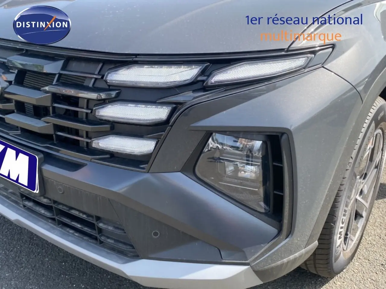 Gros plan sur l’avant droit du Hyundai Tucson gris Ecotronic Metal, mettant en valeur la calandre et les phares LED distinctifs.