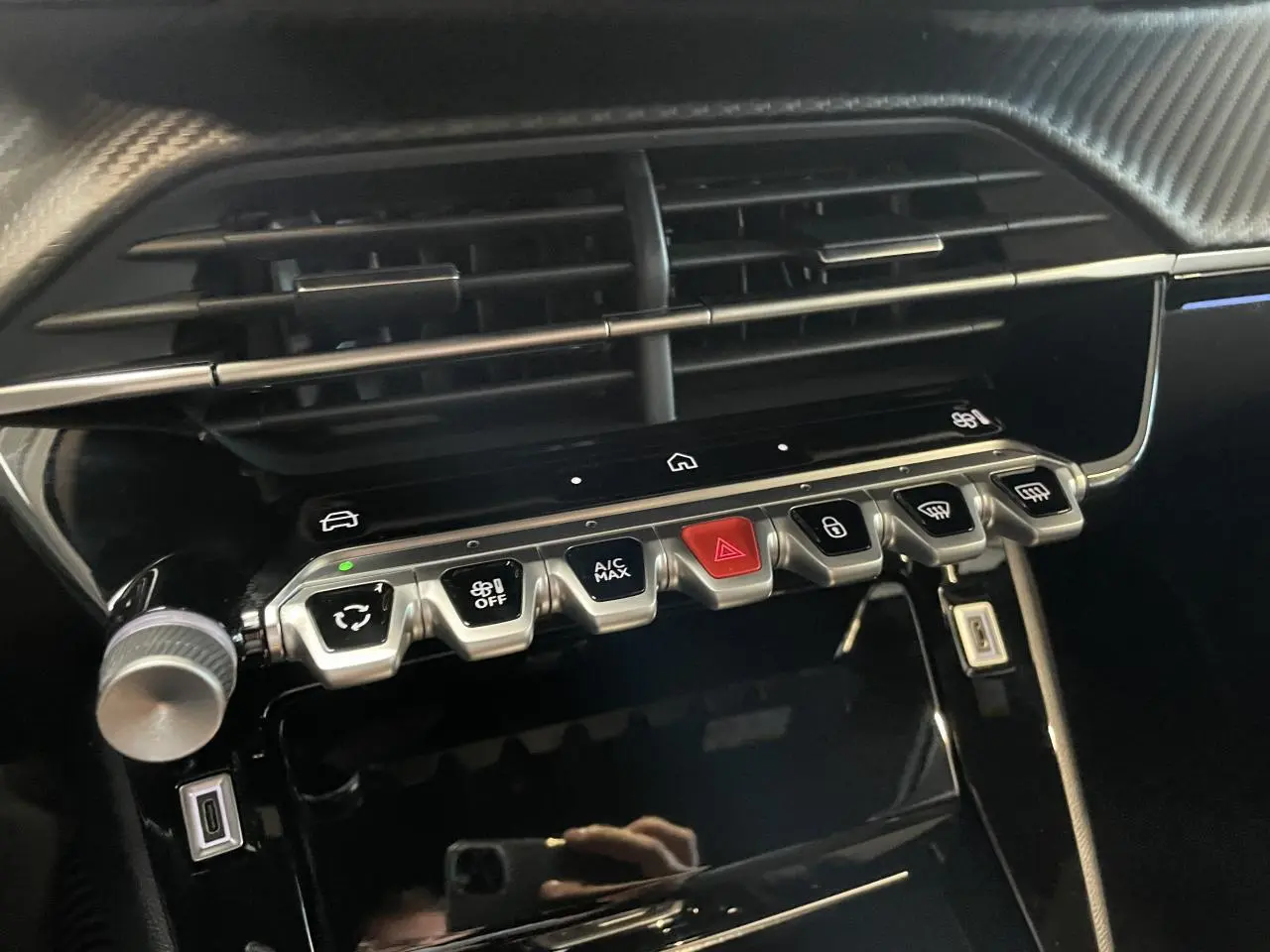 Détail intérieur du tableau de bord du Peugeot 2008 bleu, montrant les commandes de climatisation et les aérateurs.
