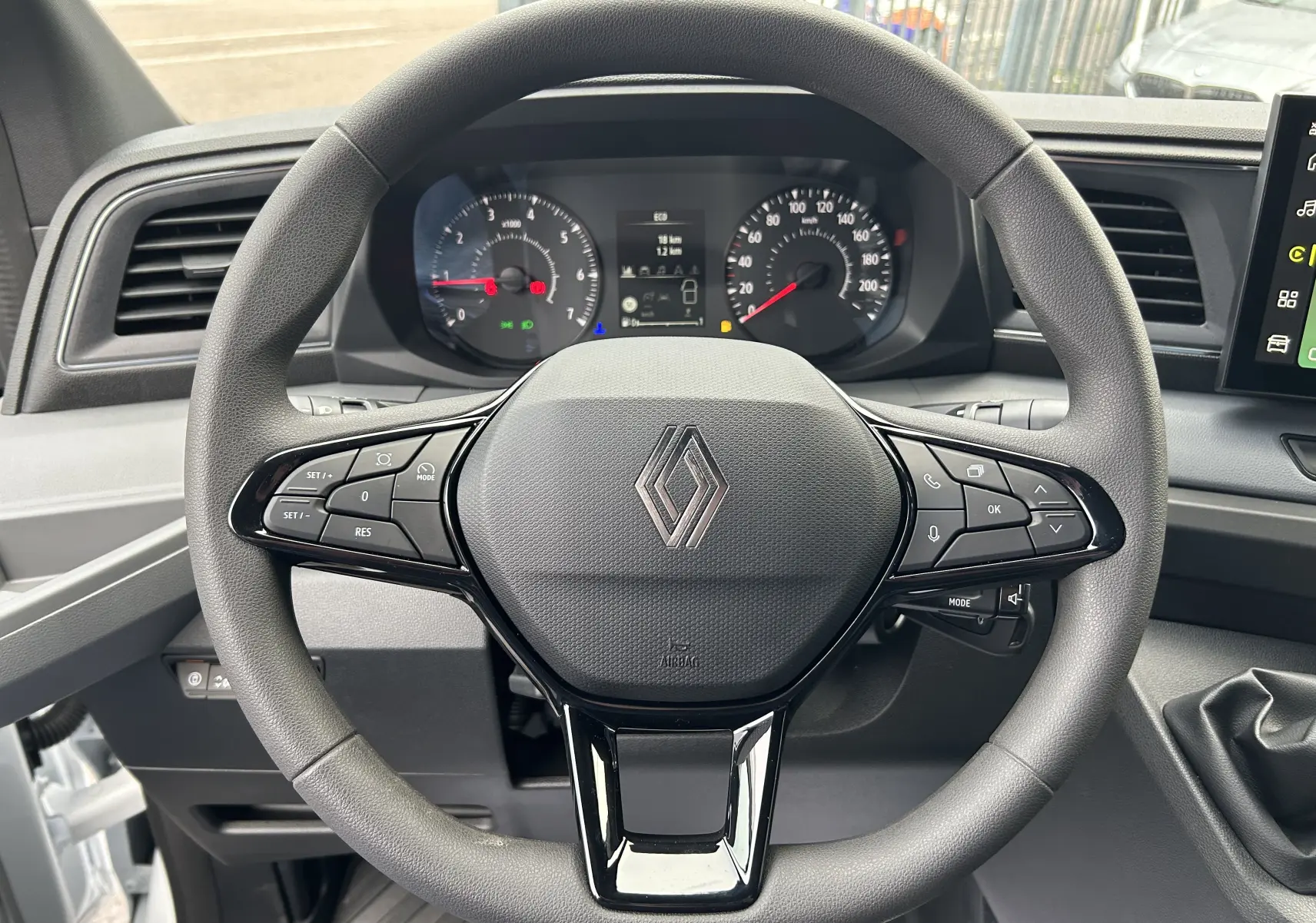 Vue rapprochée du volant noir du Renault Master 2026 avec commandes intégrées et tableau de bord visible en arrière-plan.