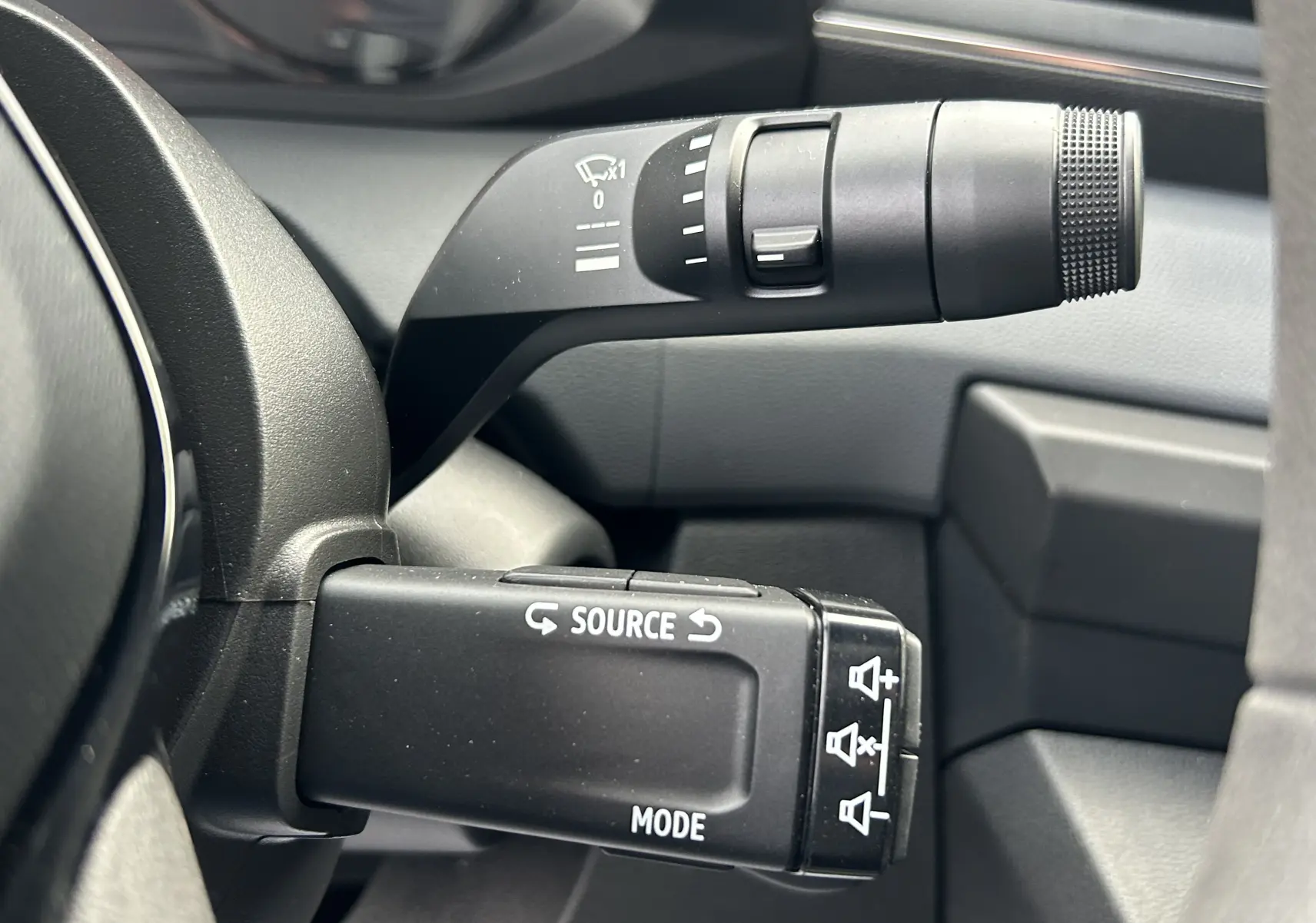Gros plan sur les commandes au volant du Renault Master 2026, boutons noirs avec inscriptions blanches, intérieur gris.