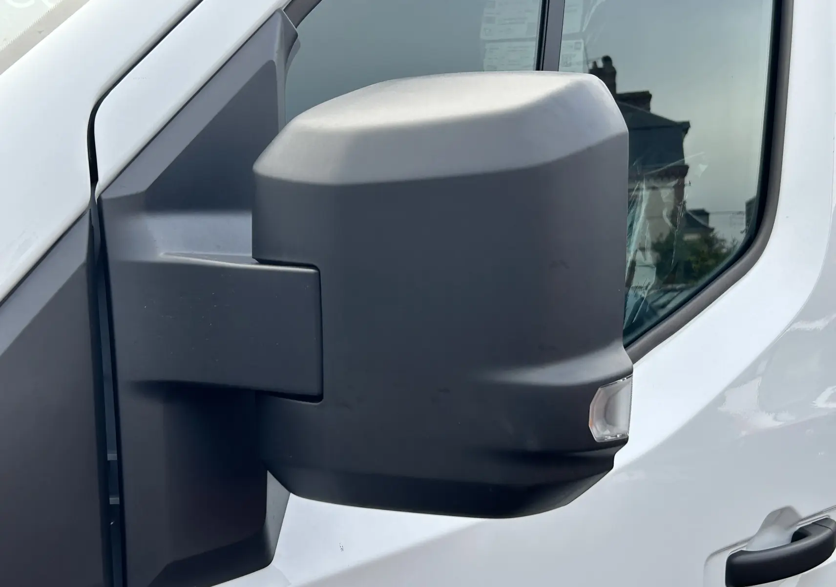 Rétroviseur latéral droit noir sur Renault Master blanc, vue rapprochée sur la portière avant.