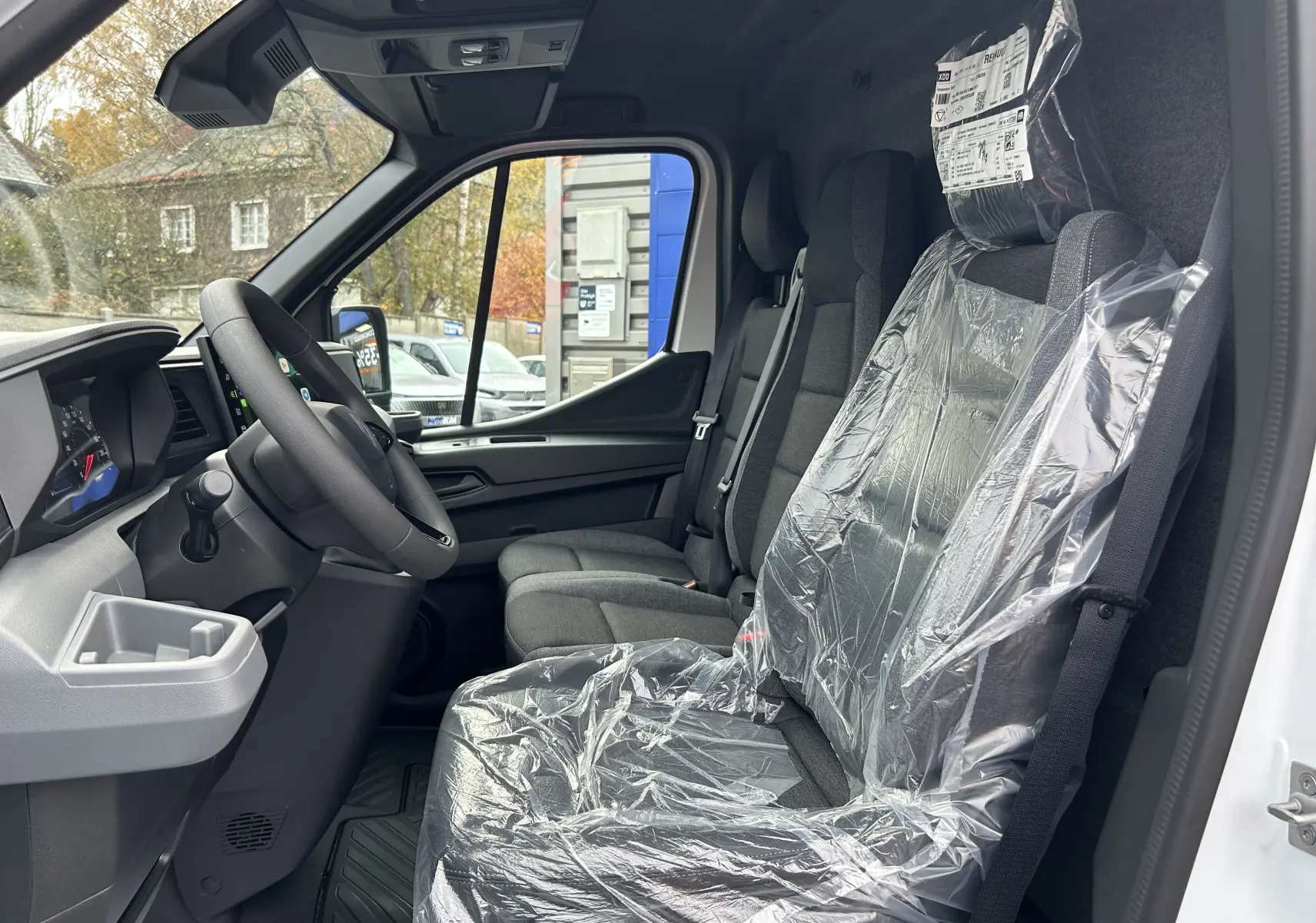 Vue intérieure côté conducteur du Renault Master blanc, montrant les sièges avant avec protection plastique et le volant.