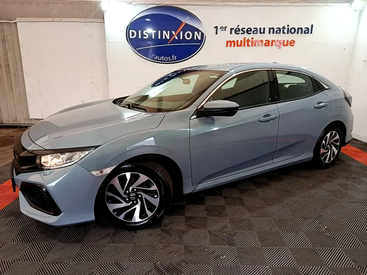 Honda Civic 1.0 i-VTEC Exclusive gris clair vue 3/4 avant droit en intérieur showroom avec jantes bicolores.
