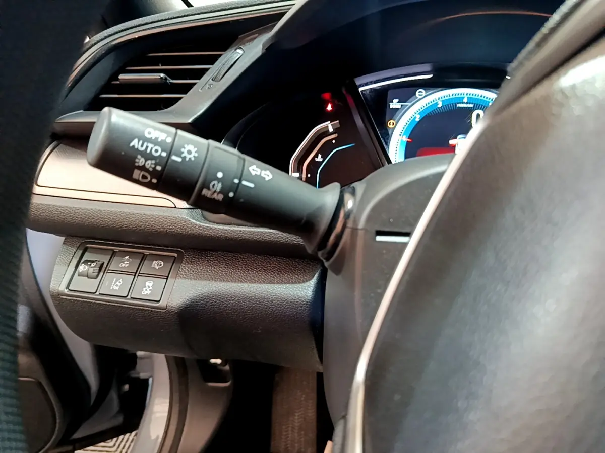 Gros plan sur la manette d'éclairage et le tableau de bord numérique de la Honda Civic 1.0 i-VTEC Exclusive 2020.