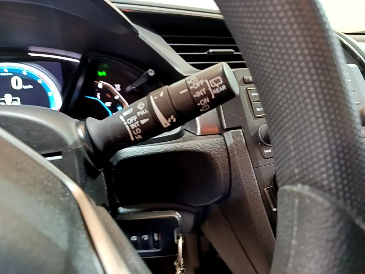 Gros plan sur la manette d'essuie-glace à gauche du volant en cuir dans l'habitacle sombre de la Honda Civic 2020.