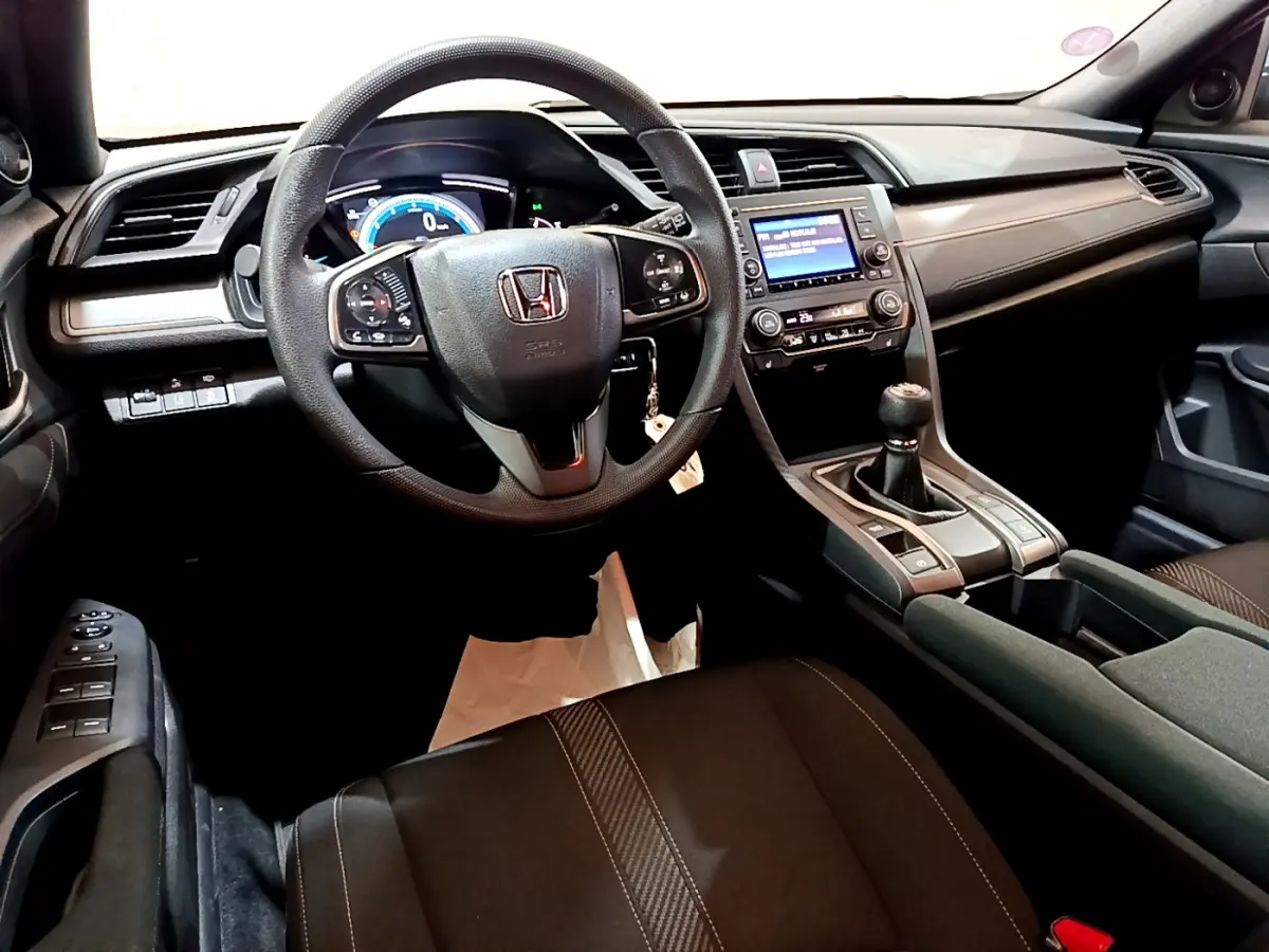 Intérieur noir de la Honda Civic 1.0 i-VTEC 2020, vue depuis le siège conducteur sur le volant et la console centrale avec boîte manuelle.